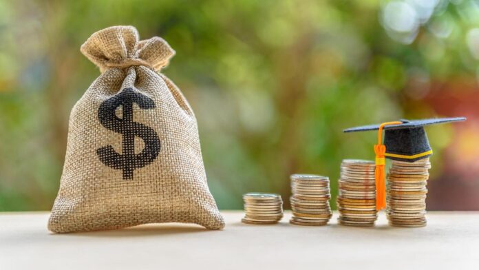 Education expense or student loan for post secondary education concept : Dollar bag, graduation cap on row of coins on a table, depicts loan or money designed to help students pay for associated fees